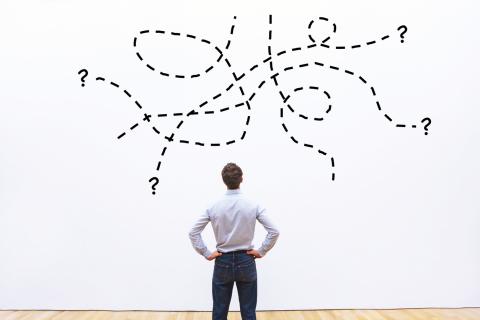 Man looking at tangled lines with question marks