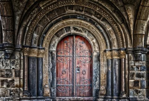 An image of an old door set in an ornate wall